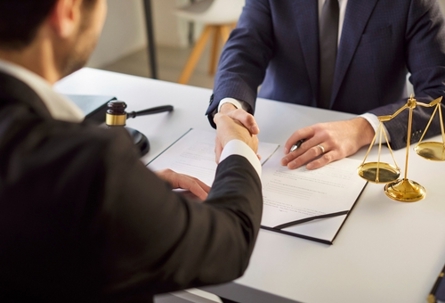 Close up shot of a professional lawyer or attorney shaking hands with a client in an office during a negotiation. Meeting focused on contracts, deals, partnerships, and legal agreements.