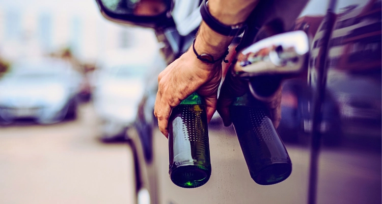A driver with a bottle of liquior on his hand